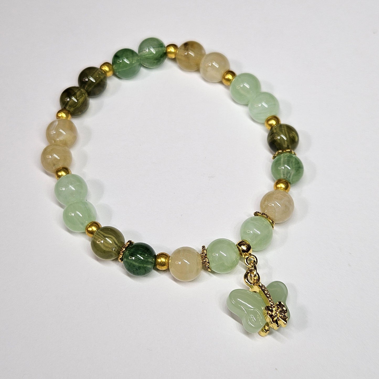 Beaded bracelet with green and beige stones on a white background